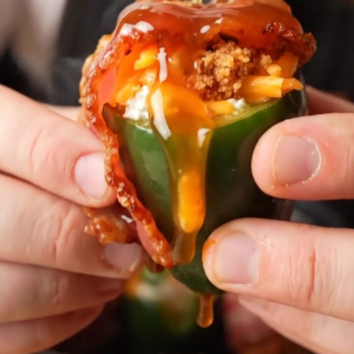 A close-up shot of crispy bacon-wrapped jalapeño poppers with bubbling cheese filling.
