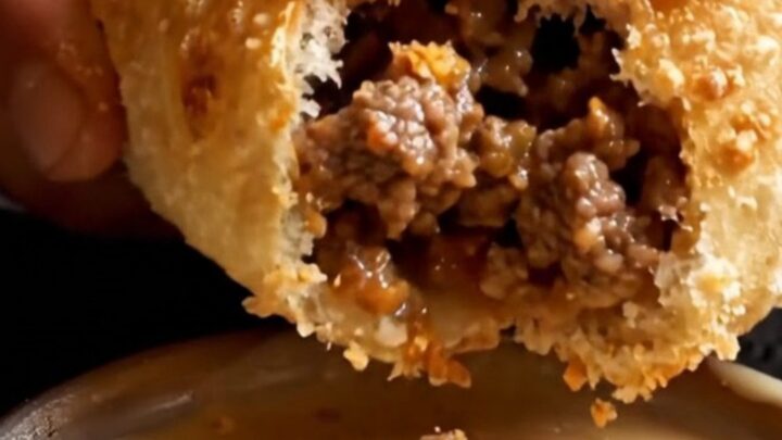 Golden-brown crispy Egyptian hawawshi pita sliced in half, showing juicy spiced ground beef inside.