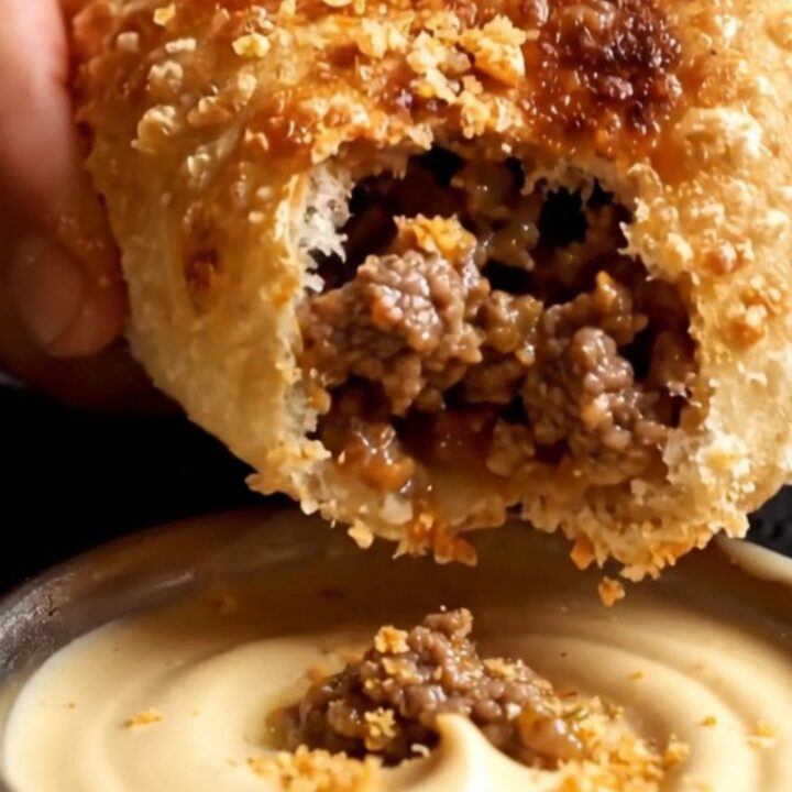 Golden-brown crispy Egyptian hawawshi pita sliced in half, showing juicy spiced ground beef inside.