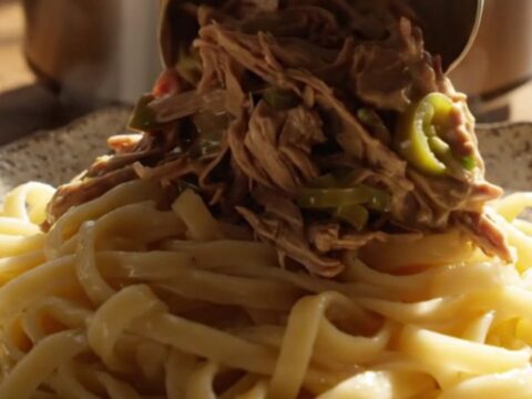 A close-up of tender shredded beef in a creamy jalapeño ranch gravy served over buttered egg noodles.