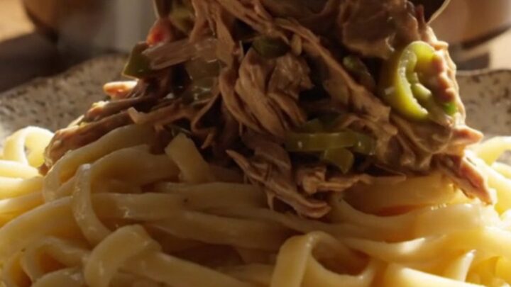 A close-up of tender shredded beef in a creamy jalapeño ranch gravy served over buttered egg noodles.