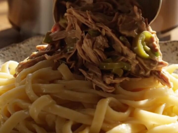 A close-up of tender shredded beef in a creamy jalapeño ranch gravy served over buttered egg noodles.