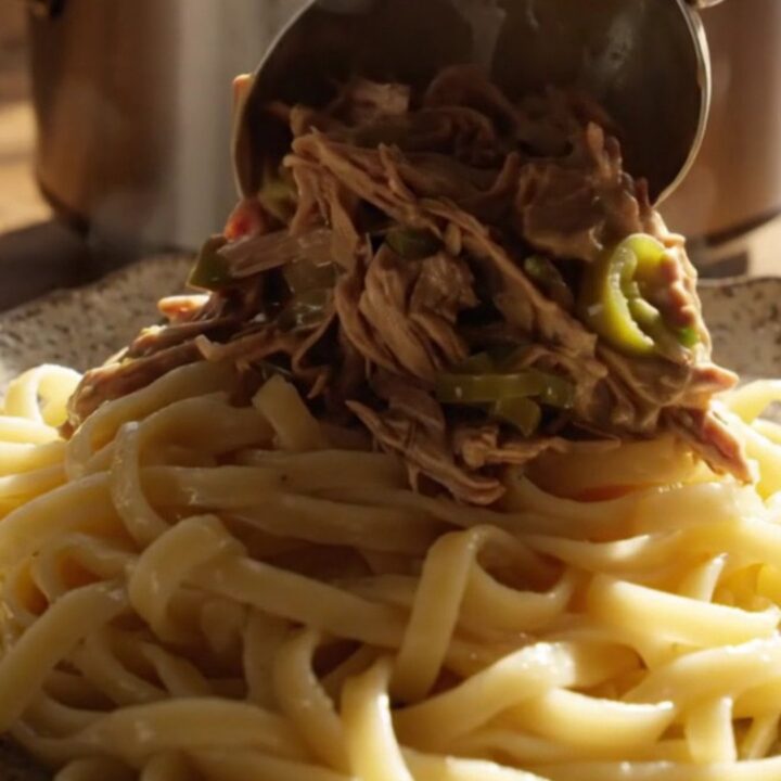 A close-up of tender shredded beef in a creamy jalapeño ranch gravy served over buttered egg noodles.