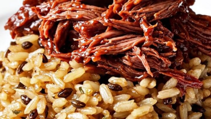 A ruby-red cranberry-orange braised beef roast served over wild rice with fresh rosemary garnishes.