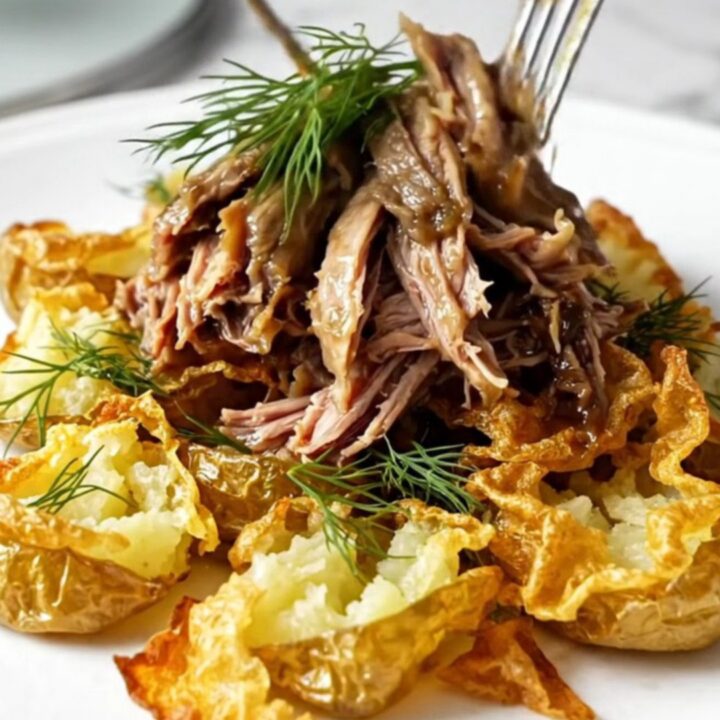 A close-up of tender shredded beef in a tangy butter sauce with fresh dill garnishes.