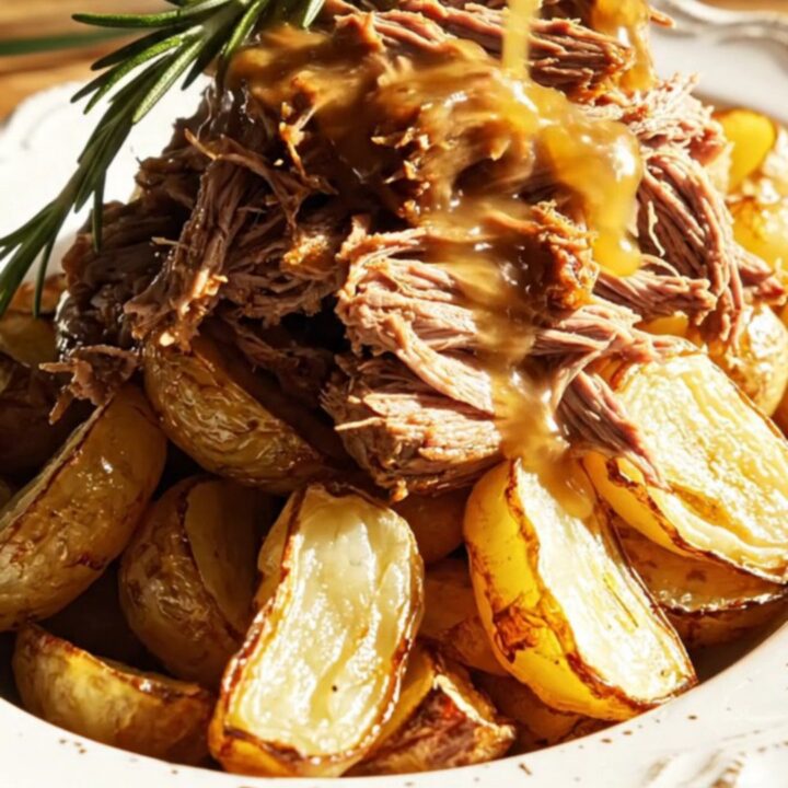 A golden honey-mustard shredded beef roast served on a plate with roasted fingerling potatoes.