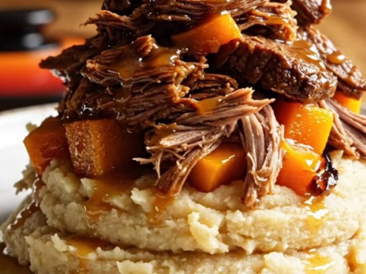 A close-up of shredded apple cider beef and tender butternut squash served over creamy mashed potatoes.