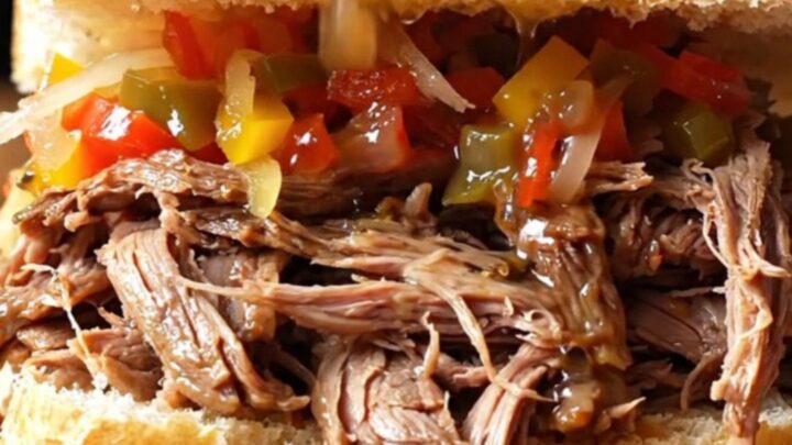 A close-up view of a crusty French roll overflowing with juicy, shredded Italian beef and spicy giardiniera.