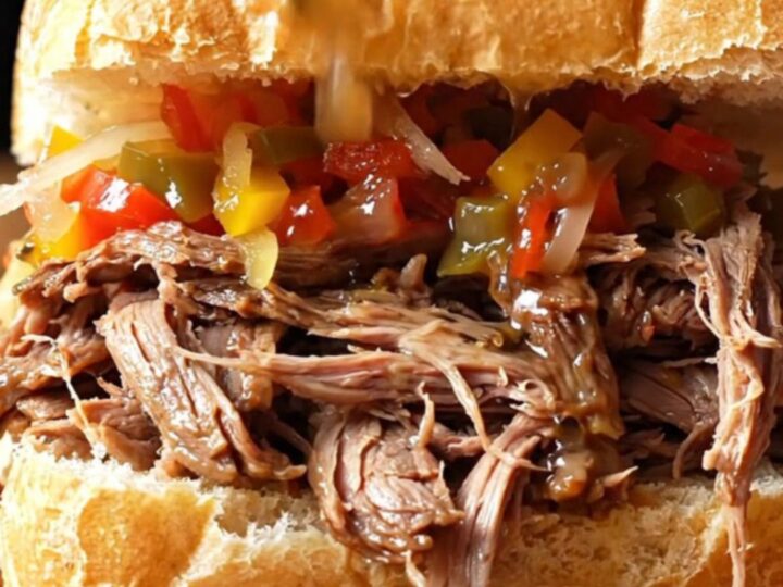 A close-up view of a crusty French roll overflowing with juicy, shredded Italian beef and spicy giardiniera.