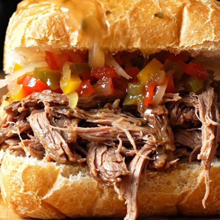 A close-up view of a crusty French roll overflowing with juicy, shredded Italian beef and spicy giardiniera.
