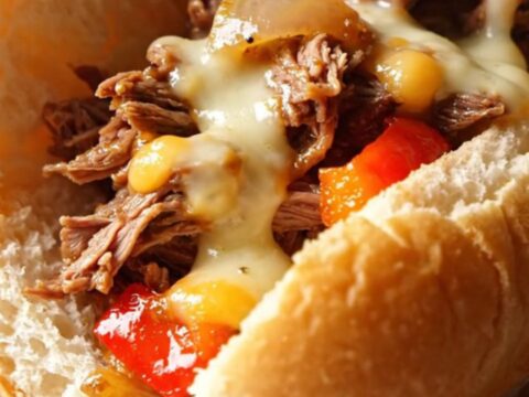 A delicious Philly cheesesteak sandwich filled with shredded ribeye, peppers, and melted cheese.