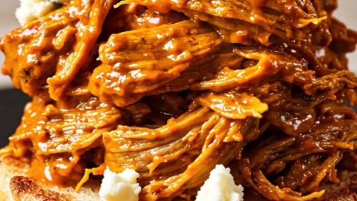A close-up shot of shredded Buffalo beef piled high on a toasted brioche bun with blue cheese crumbles.