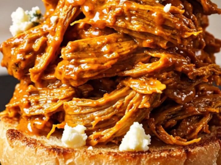 A close-up shot of shredded Buffalo beef piled high on a toasted brioche bun with blue cheese crumbles.