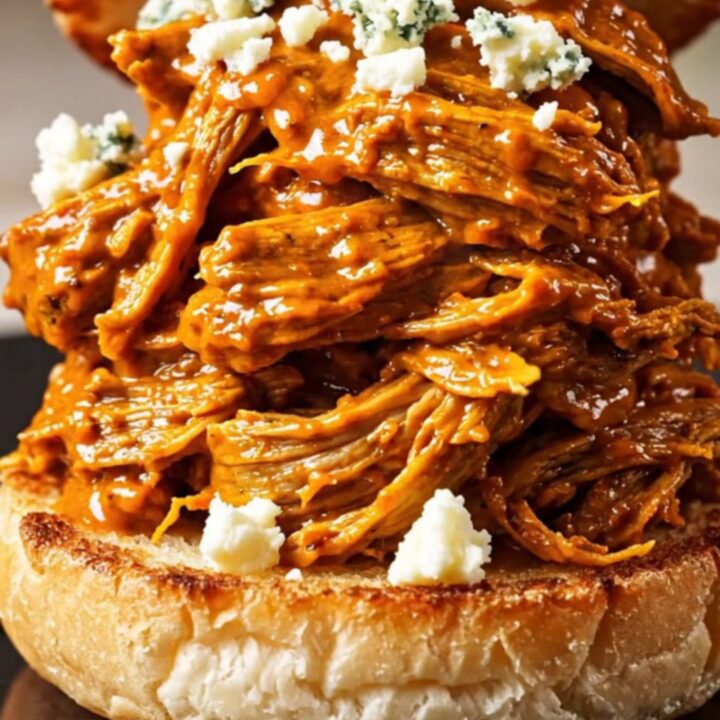 A close-up shot of shredded Buffalo beef piled high on a toasted brioche bun with blue cheese crumbles.