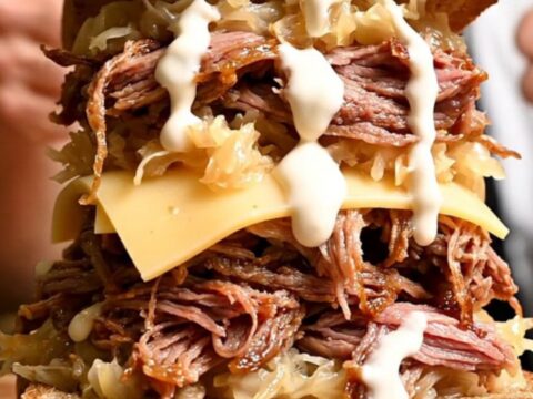 A close-up shot of a pastrami-spiced brisket being pulled apart with two forks, revealing tender, juicy meat.