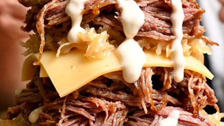 A close-up shot of a pastrami-spiced brisket being pulled apart with two forks, revealing tender, juicy meat.