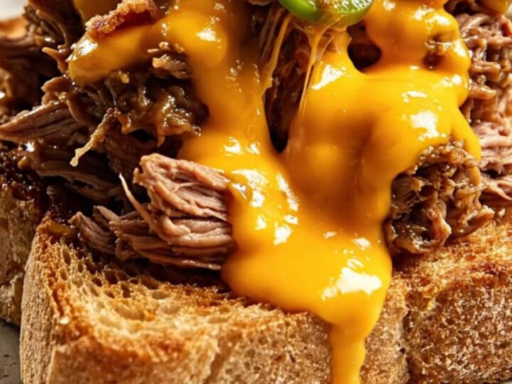 A close-up shot of creamy jalapeño popper shredded beef piled high on toasted sourdough bread.