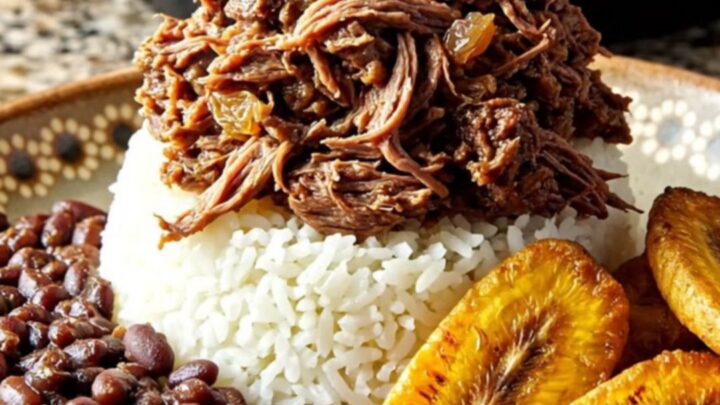 A steaming bowl of Cuban Picadillo with shredded sirloin, golden raisins, and olives served over white rice.