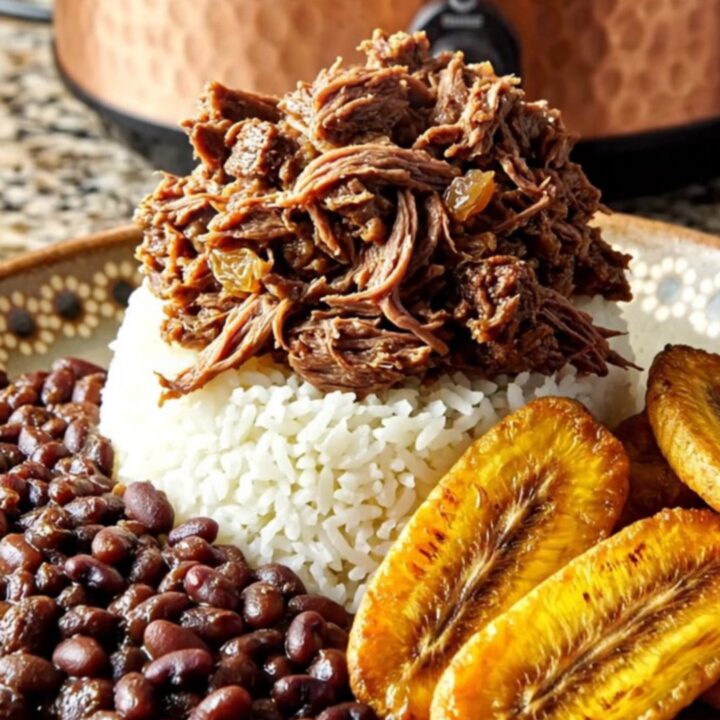 A steaming bowl of Cuban Picadillo with shredded sirloin, golden raisins, and olives served over white rice.