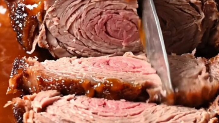 Close-up of a slow-cooked brisket being pulled apart with two forks, showing a dark bark and glossy glaze.