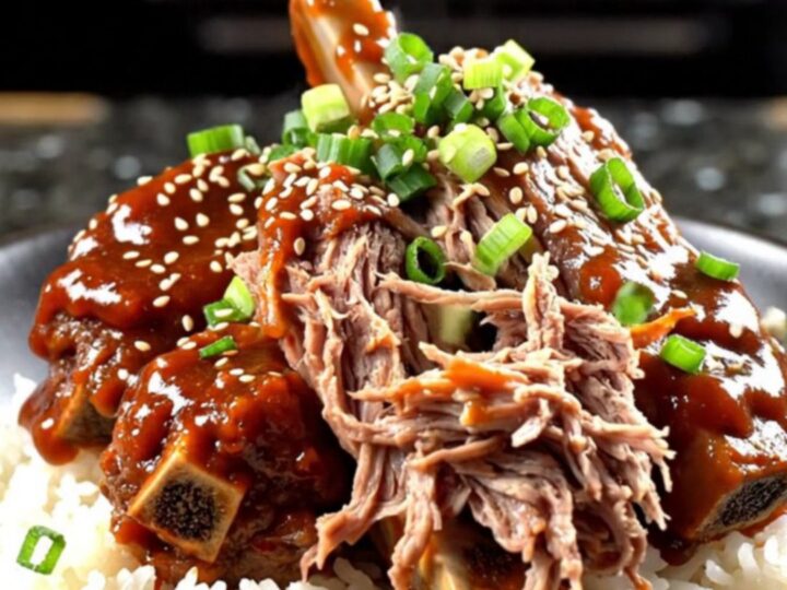A close-up of tender beef short ribs in a glossy red Gochujang glaze served over jasmine rice.