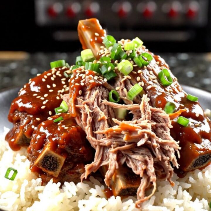 A close-up of tender beef short ribs in a glossy red Gochujang glaze served over jasmine rice.