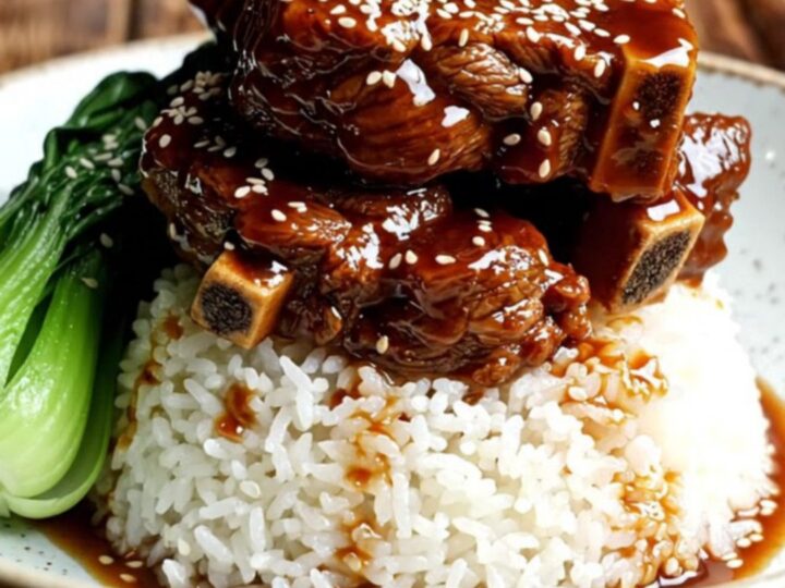 A close-up of tender, glossy beef short ribs glazed in a dark, mahogany hoisin sauce with star anise.