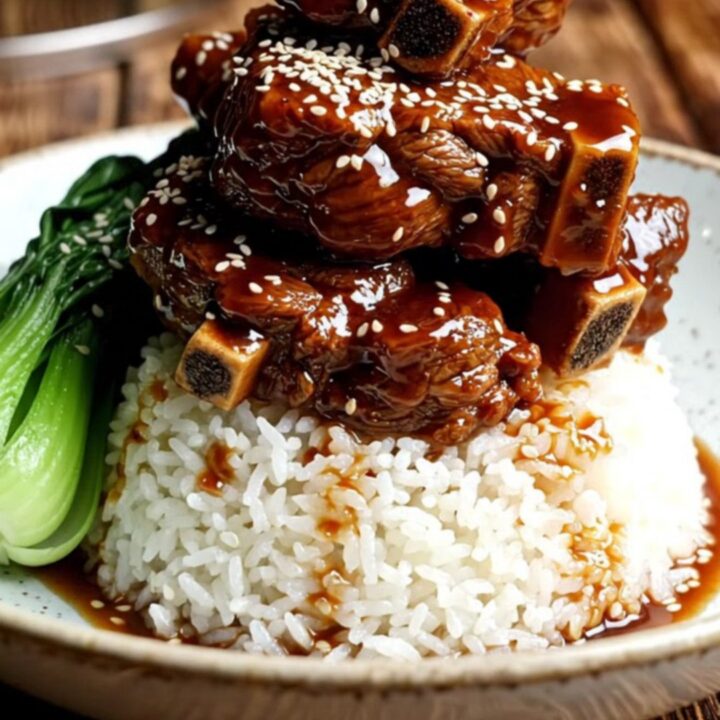 A close-up of tender, glossy beef short ribs glazed in a dark, mahogany hoisin sauce with star anise.