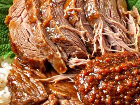 A ceramic slow cooker filled with tender, sliced Korean doenjang-braised beef brisket garnished with fresh scallions