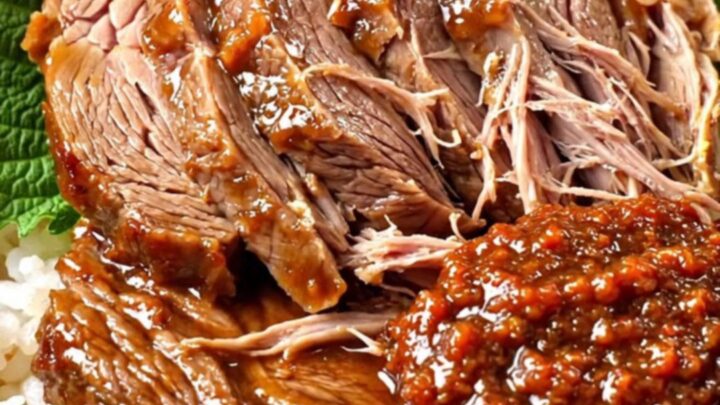 A ceramic slow cooker filled with tender, sliced Korean doenjang-braised beef brisket garnished with fresh scallions