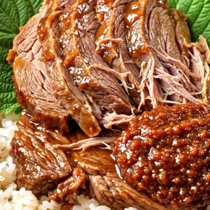 A ceramic slow cooker filled with tender, sliced Korean doenjang-braised beef brisket garnished with fresh scallions