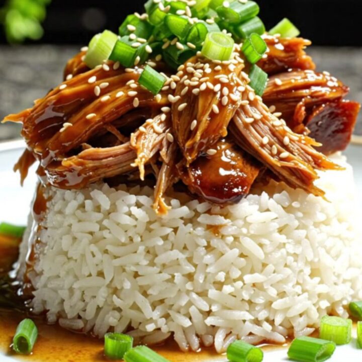 A close-up shot of shredded Hawaiian pineapple teriyaki brisket topped with green onions and sesame seeds.
