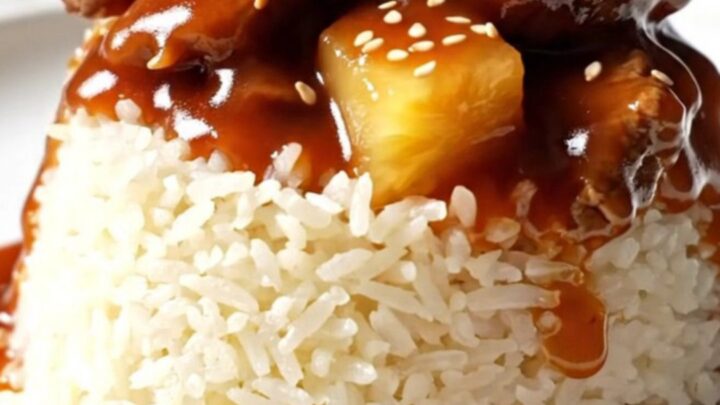A glossy sweet and sour pepper steak served over jasmine rice in a ceramic bowl.