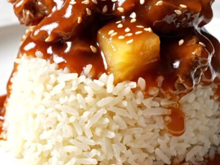 A glossy sweet and sour pepper steak served over jasmine rice in a ceramic bowl.