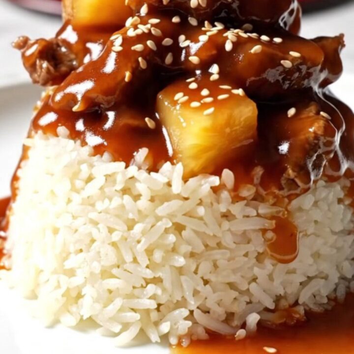 A glossy sweet and sour pepper steak served over jasmine rice in a ceramic bowl.