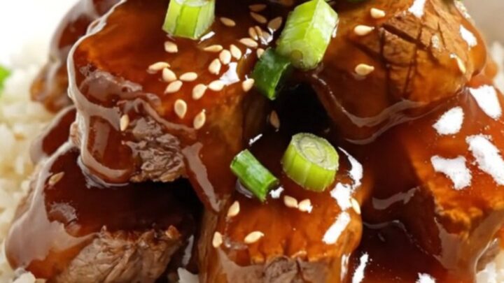 A black slow cooker filled with sticky honey-Sriracha steak bites glistening under warm kitchen light.