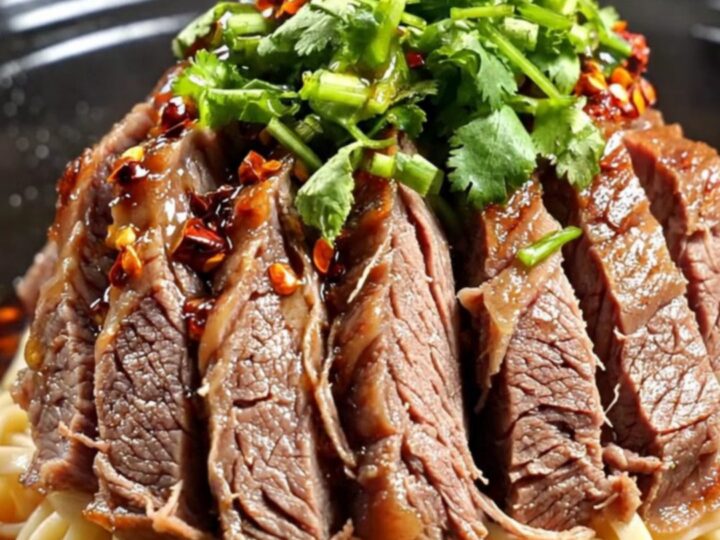 A close-up shot of tender, marbled beef shank slices in a dark, glossy, crimson Mala chili oil broth.
