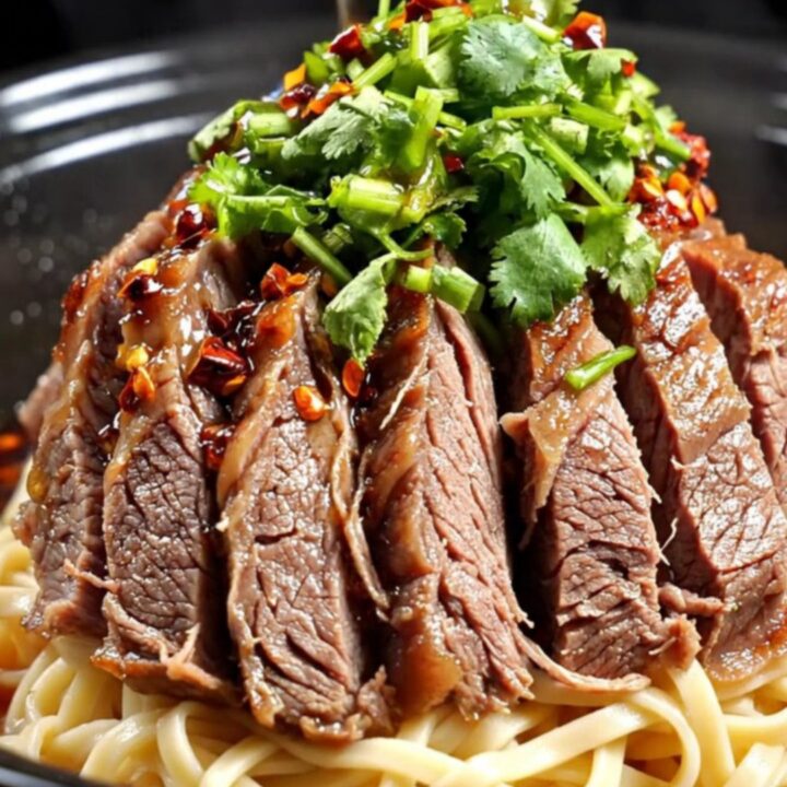 A close-up shot of tender, marbled beef shank slices in a dark, glossy, crimson Mala chili oil broth.