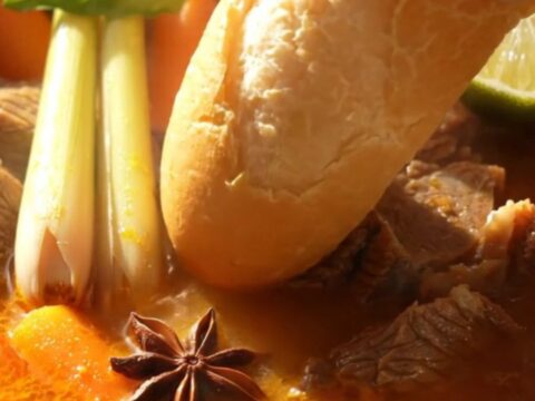 A steaming bowl of Vietnamese Bo Kho beef stew with carrots and fresh Thai basil.