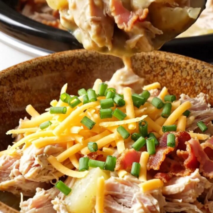 A creamy one-pot chicken and potato dish in a white slow cooker, topped with bacon and cheddar.