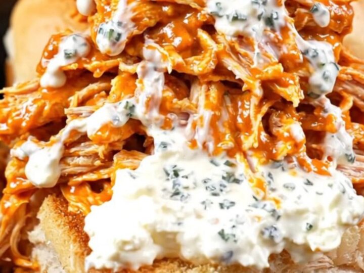 A close-up of shredded buffalo chicken on Hawaiian rolls topped with blue cheese and celery.