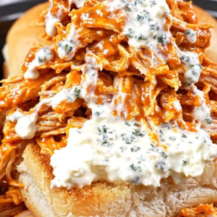 A close-up of shredded buffalo chicken on Hawaiian rolls topped with blue cheese and celery.
