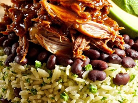 A vibrant burrito bowl featuring shredded chipotle honey lime chicken, black beans, avocado, and cilantro rice.