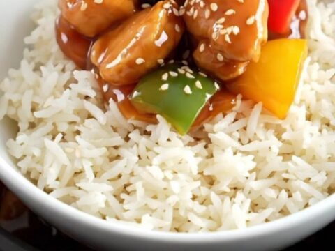 A glossy sweet and sour chicken dish with pineapple and peppers in a ceramic slow cooker.