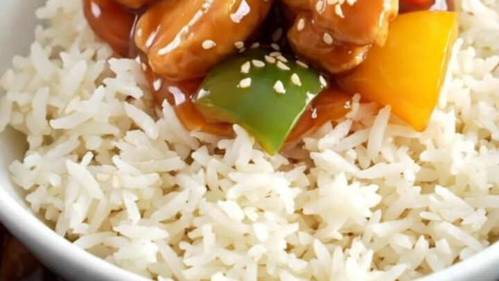 A glossy sweet and sour chicken dish with pineapple and peppers in a ceramic slow cooker.
