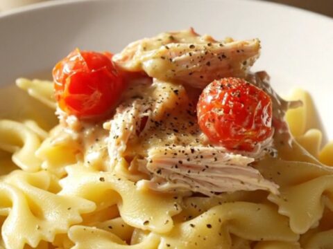 A close-up of creamy Boursin chicken served over farfalle pasta with fresh herbs and cracked black pepper.