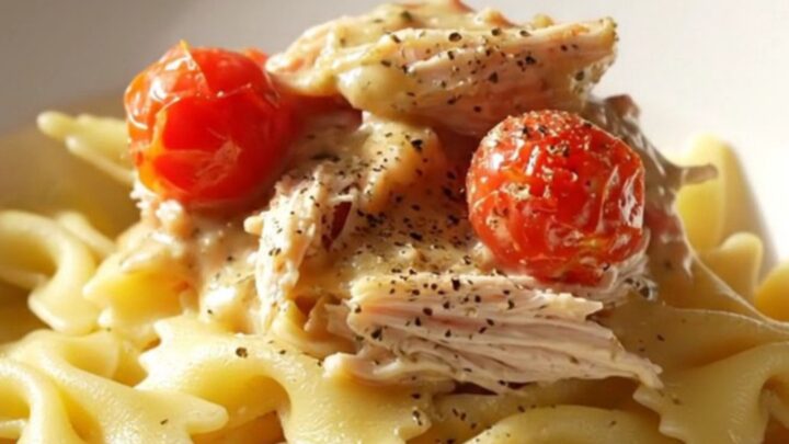 A close-up of creamy Boursin chicken served over farfalle pasta with fresh herbs and cracked black pepper.