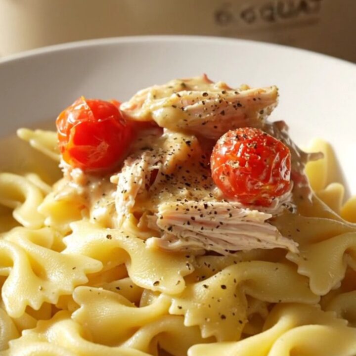 A close-up of creamy Boursin chicken served over farfalle pasta with fresh herbs and cracked black pepper.