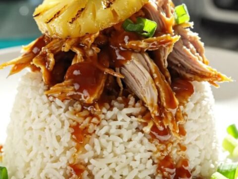 A close-up of shredded Huli Huli chicken in a turquoise ceramic slow cooker with steam rising.