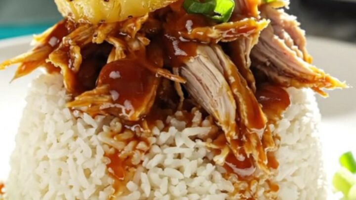A close-up of shredded Huli Huli chicken in a turquoise ceramic slow cooker with steam rising.
